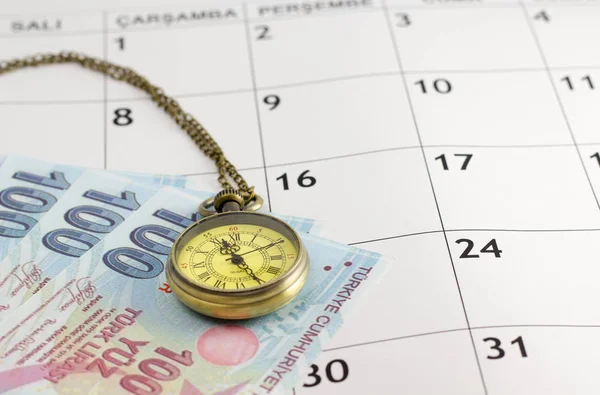 pocket watch and turkish banknotes on calendar