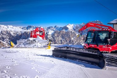 Alpler Dağlarında iki Ratrack makinesi. Mavi gökyüzü ve beyaz yamaçlar.