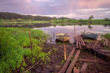 Gün batımında Rus Nehri Nerl üzerinde bir satır tekne resmi. Mavi gökyüzü ve inanılmaz bulutlar