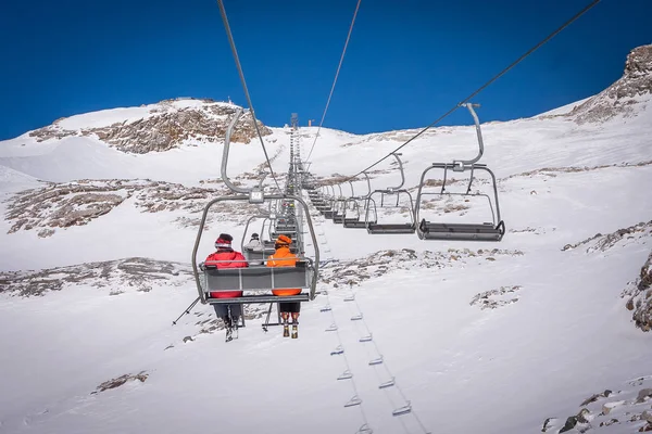 Un par de peopchair lift en la estación de esquí austriaca montan la silla de esquí levantan la montaña juntos mientras se sientan cerca el uno del otro teniendo un rato de diversión durante un día de snowboard en oregon . —  Fotos de Stock