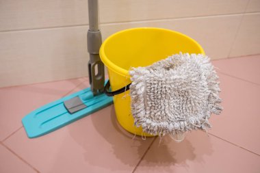 banyo üst görünümünde sarı kova, paspas ve bez