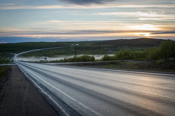 Asfaltová silnice s mlhou při západu slunce. — Stock fotografie