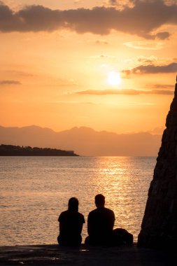 İnsanlar Cefalu, Sicilya 'da günbatımının tadını çıkarıyor.