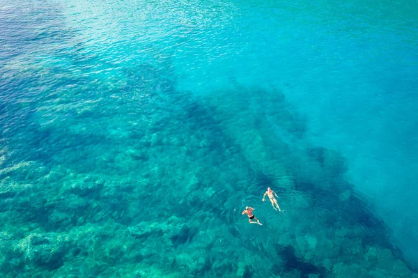 Vista aérea da praia de Trsteno, em Montenegro, perto de Budva, uma bela baía com uma costa rochosa, água azul, pessoas se banham em águas claras — Fotografia de Stock