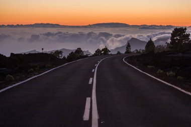 Beautiful turn of the road above the clouds during a sunset on Tenerife island, Spain. clipart