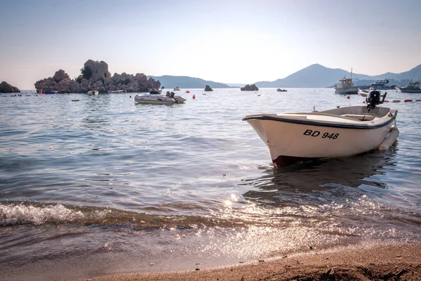 ПРЖНО, МОНТЕНЕГРО - 045 июля: Вид на рыбацкую лодку на пляже Пржно в Черногории на закате. Солнечные лучи прекрасно отражаются от воды — стоковое фото