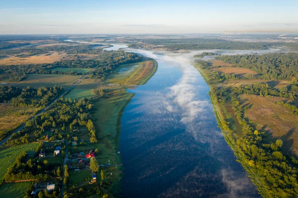 Beautiful aerial view of the river. Early morning landscape. Foggy river. River valley in the morning fog at sunrise. View from above.