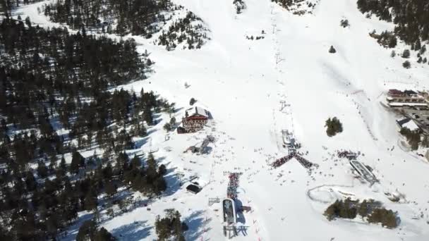 Vista aérea movimento suave ao longo das pistas de esqui na estância de esqui de Grandvalira em Andorra. Fila de pessoas em elevadores de cadeira. Magníficas montanhas nevadas e céu azul. Paisagem de inverno. Visão de cima para baixo. — Vídeo de Stock