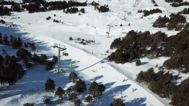 Flygfoto jämn rörelse längs skidbackarna i skidorten Grandvalira i Andorra. Skidliftar med skidåkare. Magnifika snöiga berg och blå himmel. Vinterlandskap. ovanifrån. — Stockvideo