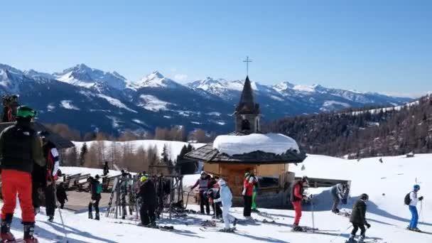 ALPE LUSIA, ITALY - 16 февраля 2020 года: Лыжники в зоне отдыха рядом с горным рестораном на фоне итальянских Доломитов. Зимние снежные лыжи солнечные дни - Горнолыжный курорт Alpe Lusia — стоковое видео