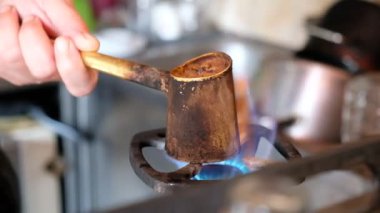 Gaz sobasının üzerinde bakır bir kafeste Türk kahvesi yapmak. Tahıl öğütme. Türk 'ün gazlı sobasında, elinde kahve var. Kahve hazırlıyorum. Gaz sobası ve yanan ateş. Bir fincan kahve.
