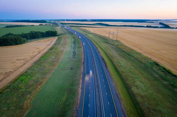 Ormanla çevrili otoban sisli bir şekilde çayırda ilerliyor. Sis kaplı bir yolun havadan görünüşü.