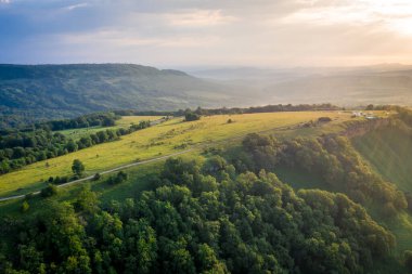 Sabahın erken saatlerinde dağlarda. Sabah güneşi ve sis vadinin arka planında dağların arkasında