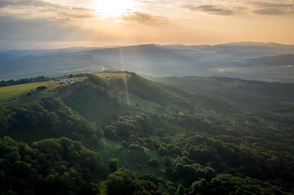 Early morning in the mountains. Morning sun and haze in the valley against the background of mountains