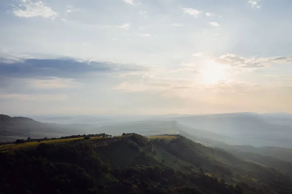 Early morning in the mountains. Morning sun and haze in the valley against the background of mountains