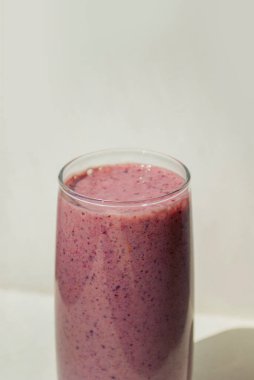 Blueberry smoothie in glass on light background with long shadows. Milk Shakes. Vitamin healthy food