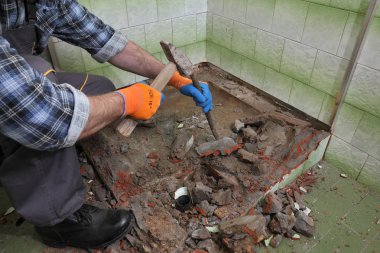 İşçiler banyodaki eski küveti ve kiremitleri çekiç ve keskiyle söker, yıkarlar.