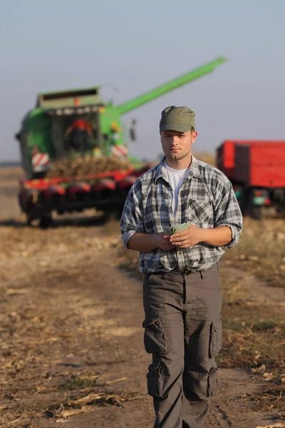 Landwirt Mit Euroschein Und Mähdrescher Hintergrund Ernstes Gesicht Maiserntekonzept — Stockfoto