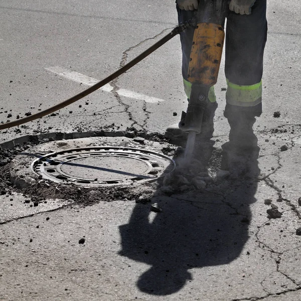 Arbeiter Auf Baustelle Reißt Asphalt Mit Presslufthammer Neben Kanalschacht — Stockfoto