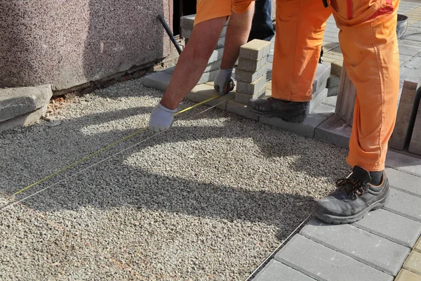 建設現場労働者コンクリートのレンガ舗装の基盤を測定 — ストック写真