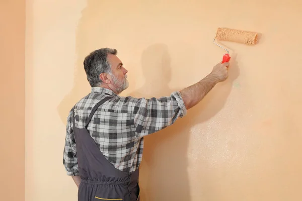 Lavoratore Pittura Parete Una Stanza Colore Arancione Con Rullo Vernice — Foto Stock