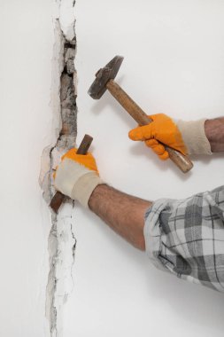 İnşaat işçisi deliğe çekiç ve keski aracı ile tuğla duvar yıkılması