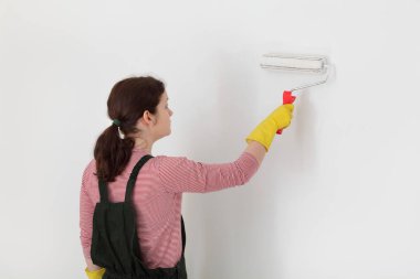 Kadın işçi boyama duvar boya silindiri aracını kullanarak beyaz