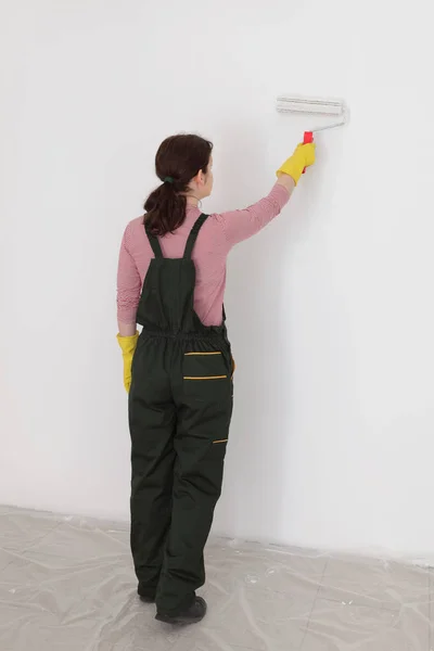 用漆辊工具画墙到白色的女工人 — 图库照片