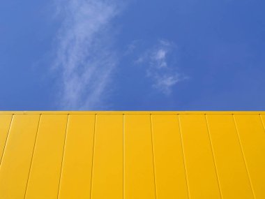 Yeni sarı metal paneli inşaat, mavi gökyüzü ve arka plan beyaz bulut ile yapı duvarına