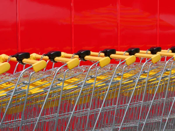 Pilha Novos Carrinhos Compras Brilhantes Supermercado Com Parede Vermelha Fundo — Fotografia de Stock