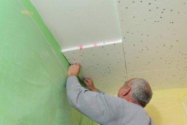 Kapalı bir odada tavana köpük yalıtım yerleştirerek işçi çalışıyor