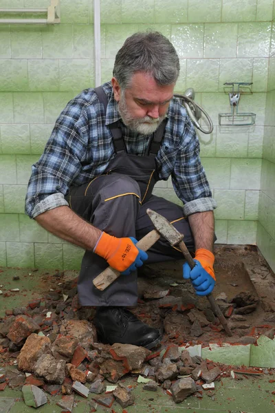 作業者は古い浴槽とタイルをハンマーで取り除き バスルームに彫る — ストック写真
