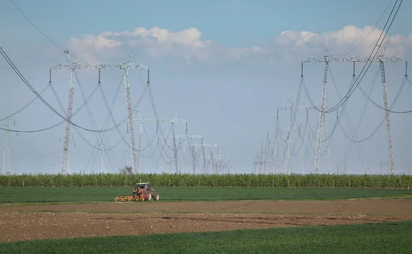 Tractor in field and high voltage lines — Stock Photo, Image