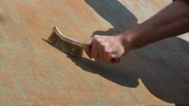 Tel fırça kullanarak eski metal plakadan pas çıkarma, aletle closeup oh el