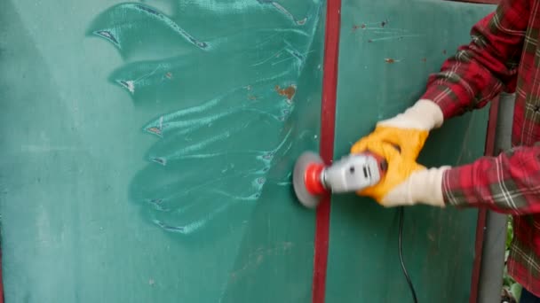 在磨床电动工具 工人手部和设备上使用钢丝刷从旧金属门上清除油漆和防锈 — 图库视频影像