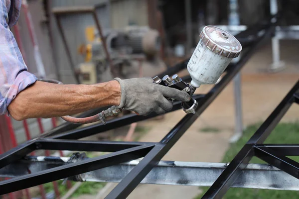 Trabajador usando pistola de pintura para pintar metal — Foto de Stock