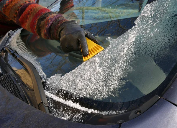 冬の風景 車のフロントガラスから手袋のスクレーピング氷の人間の手 — ストック写真