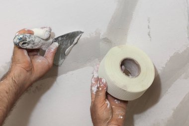 Tavandaki çatlakları onaran işçiler, lifin üzerine alçı serpiştiriyorlar.