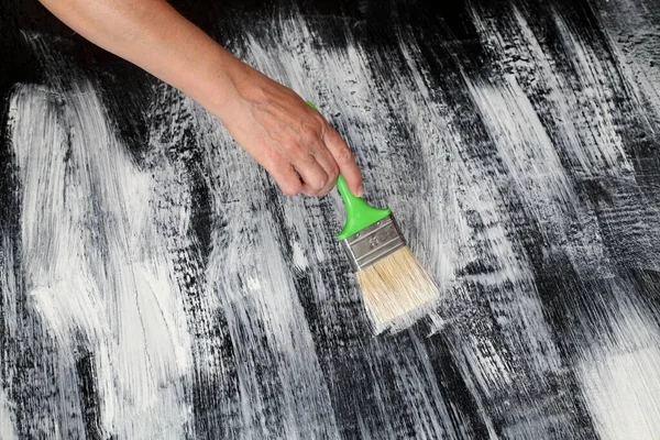 家の改装 白と黒 労働者の手とブラシとみすぼらしいシックな組み合わせに板床の絵 — ストック写真