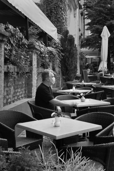 蒙面男子坐在空荡荡的咖啡店里 电晕病毒基本保护和社会距离 — 图库照片