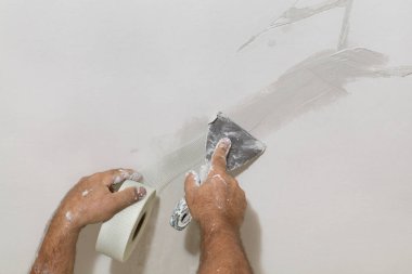 Tavandaki çatlakları onaran işçiler, lifin üzerine alçı serpiştiriyorlar.