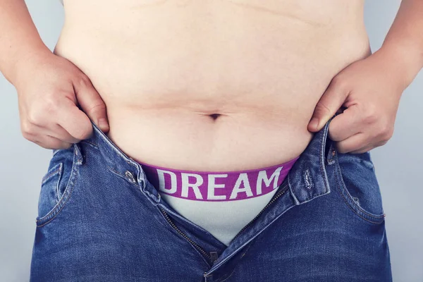 Fat woman trying to wear jeans. Overweight problems, female obesity.