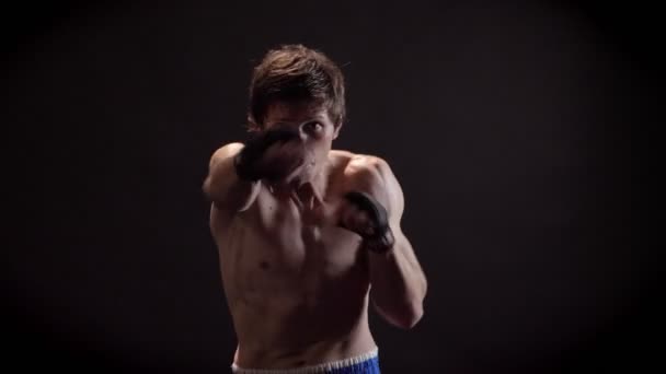 Портрет молодого кавказского топлесс боксера, бокса, борьбы с тенью, тренировки, глядя в камеру, черный фон 50 кадров в секунду — стоковое видео