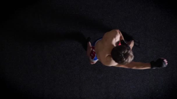 Jovem boxeador de topless caucasiano fazendo aquecimento, bater, boxe, vista superior, fundo preto. 50 fps — Vídeo de Stock