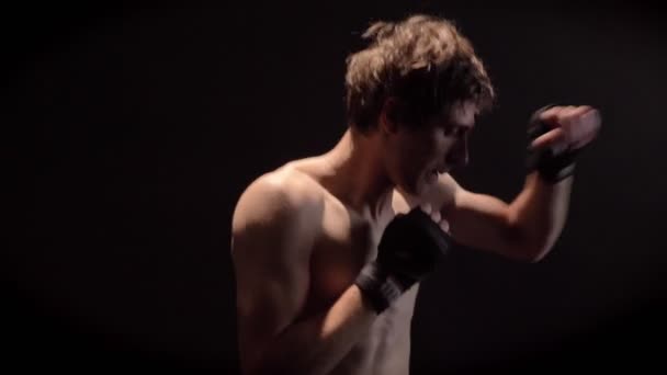 Junger kaukasischer Boxer oben ohne boxen, jab, punch, schwarzer Hintergrund, Seitenansicht 50 fps — Stockvideo