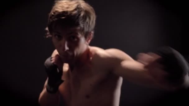 Joven boxeador caucásico en topless en la parte delantera, mirando a la cámara, jab, puñetazo, fondo negro 50 fps — Vídeo de stock