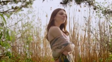 Genç zencefil elbiseli kız doğada ormandaki duruyor, köknar, Ladin dokunur, içinde bitkilerin 50 fps arka plan