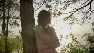 Genç güzel zencefil kameraya gülümseyen kız orman duran ağaç, Doğa, siluet, yakınındaki plajda 50 fps