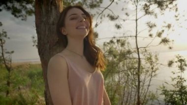 Gülümseyerek, orman duran ağaç, Doğa, siluet, yakınındaki plajda kız kameraya bakarak gülen genç güzel zencefil 50 fps