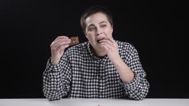 Fiatal túléld lány eszik darab csokoládét, fogamzást étrend, fekete háttér — Stock videók